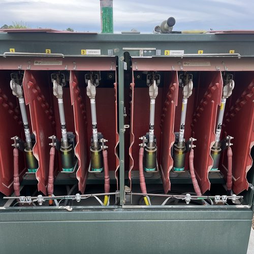 Pad-mounted switchgear with its doors open, showing six numbered compartments of elbow terminations behind red insulating barriers