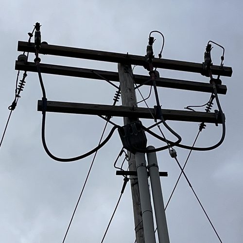 Cable risers running up a utility pole to terminations on three-phase crossarms