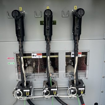 Three-phase elbow terminations landed in a switchgear cabinet, phases labeled A, B and C